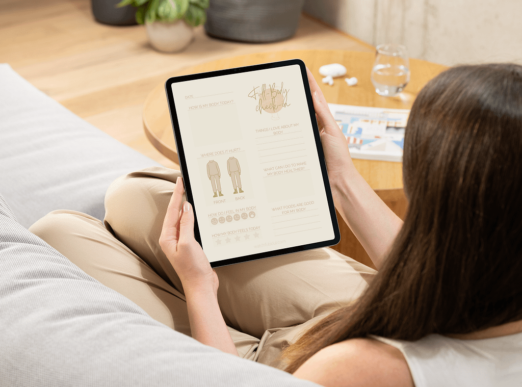 A person seated on a couch, using the ‘Full Body Check-In’ journal on a tablet to track physical sensations and self-care needs.