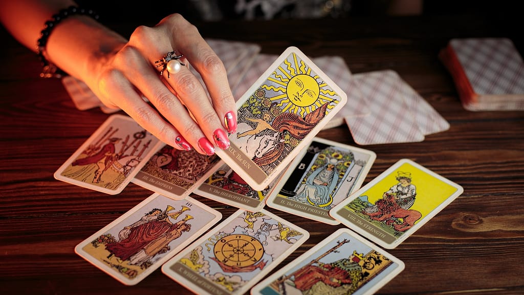 person holding the sun tarot card, with other tarot cards on the table