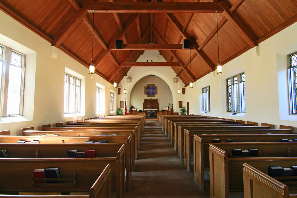 a peaceful church interior with wooden pews and light streaming through stained glass windows