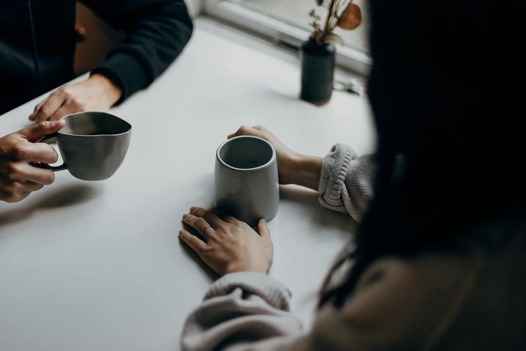 Two people having a quiet conversation over coffee, symbolising the kind of reflective, supportive space created by combining tarot with the Enneagram.