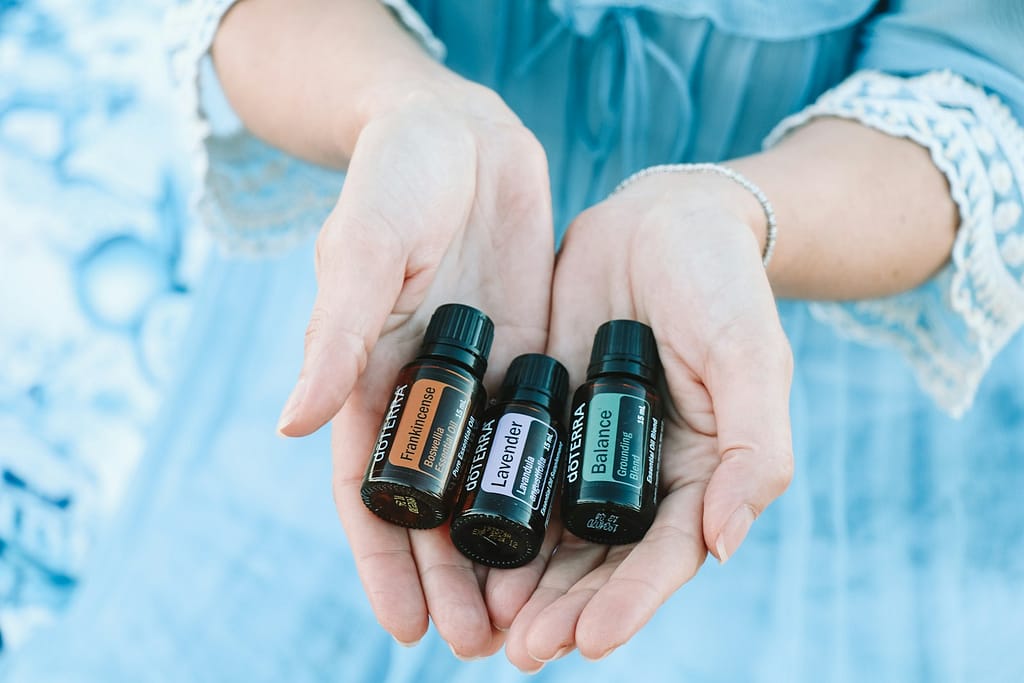 three black essential oils bottles on persons hand