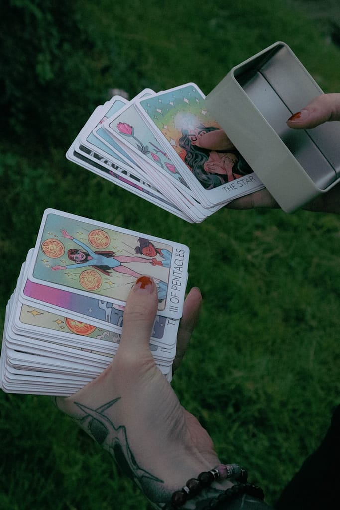 Person holding a colourful tarot deck outdoors, representing spiritual work, intuitive skill, and the reality behind paying for tarot readings