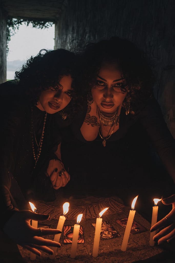 Two women engaging in a candlelit ritual, creating a mystical and enigmatic atmosphere.
