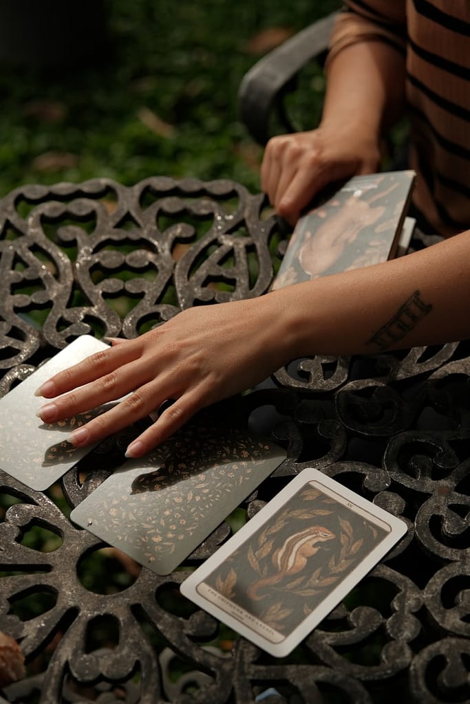 Hands arranging tarot cards on a metal table