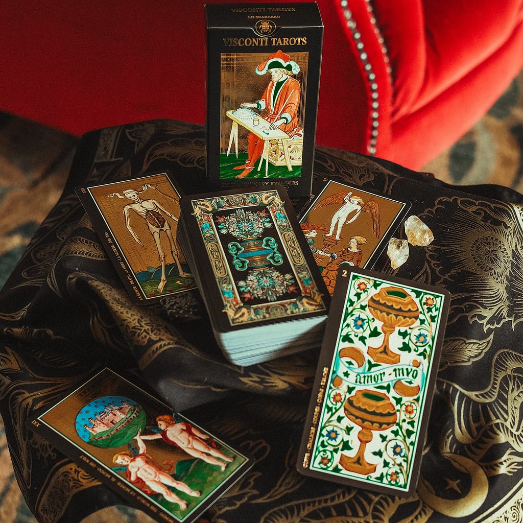 Modern reproduction of the Visconti-Sforza Tarot, the oldest tarot deck in history, showing ornate cards and box on a black cloth with crystals.