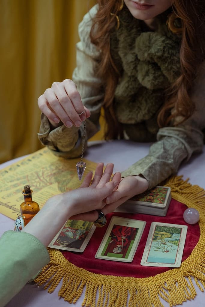 Trustworthy tarot reader working collaboratively with a client, using tarot cards and a pendulum in an open, respectful setting.