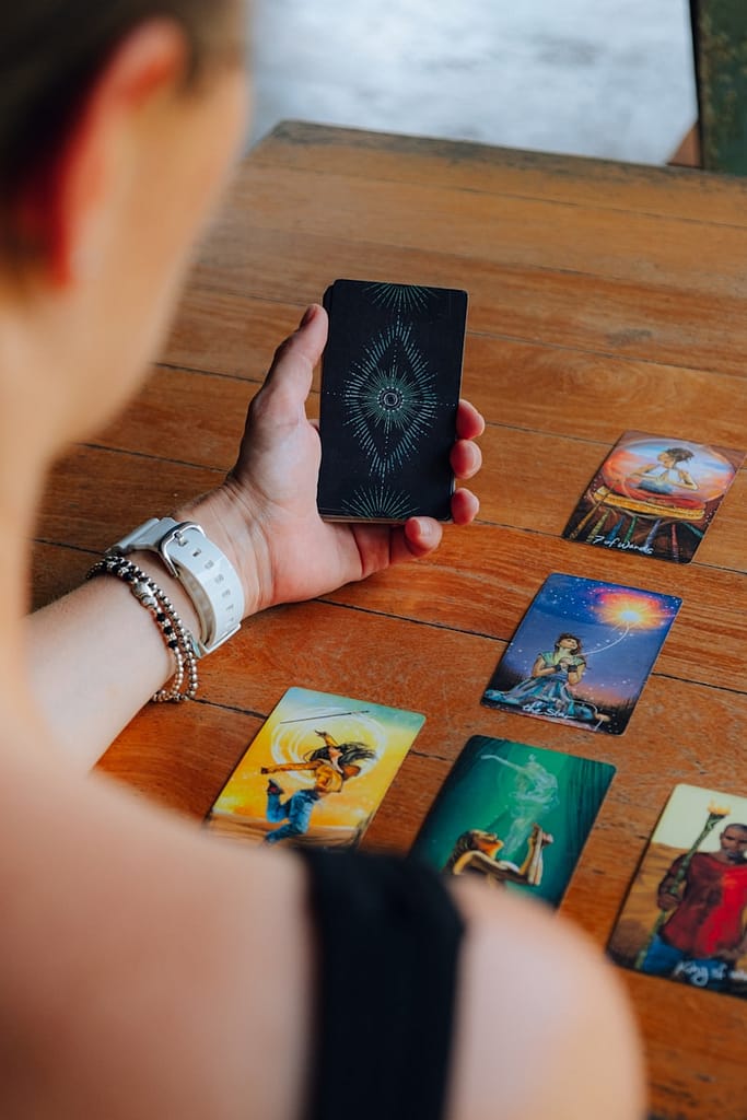 a woman holding up a tarot card on top of a wooden table