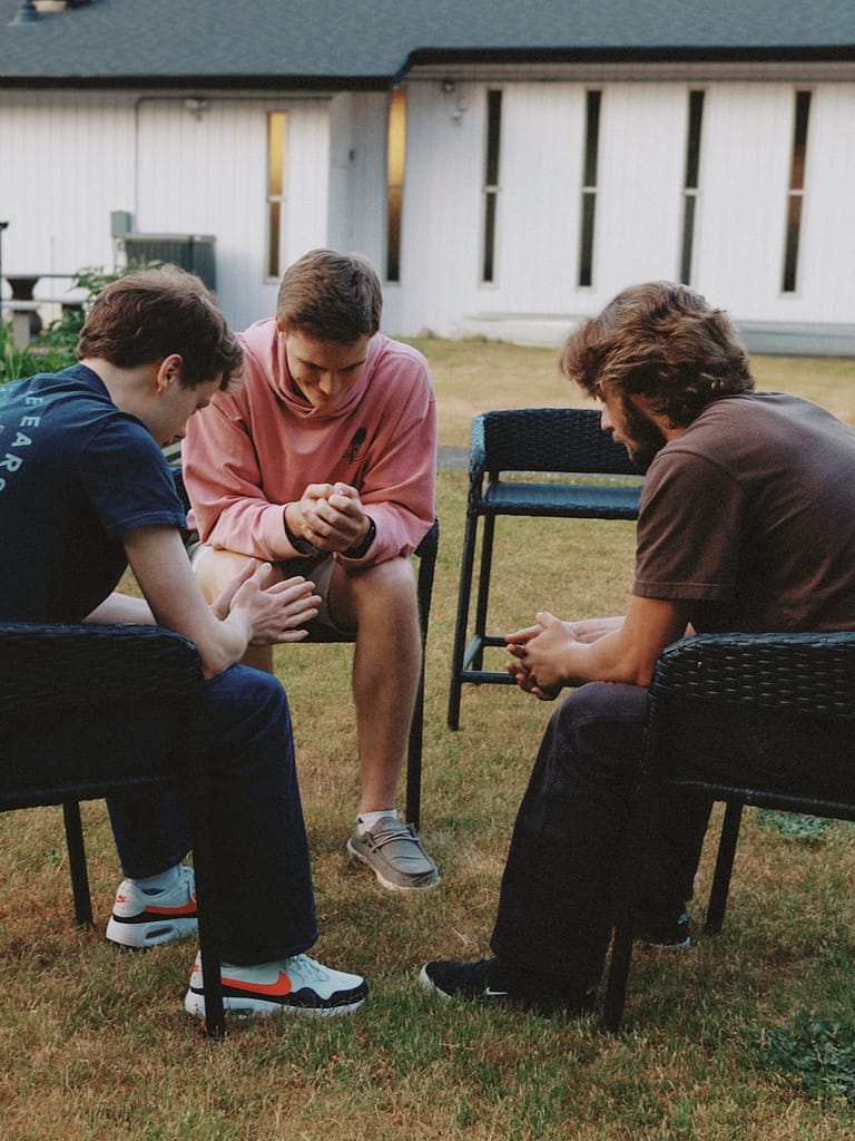 Three young men sitting in a circle chatting.