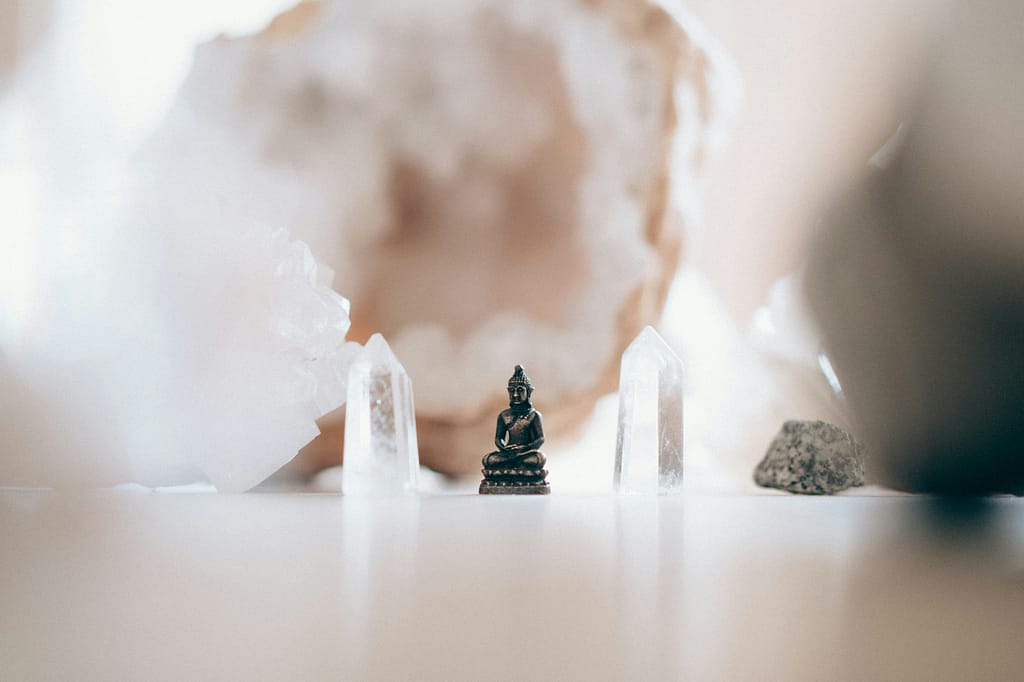 Deconstructing Faith, Tarot, And Finding Your Spiritual Flow 7 A small buddha statue surrounded by clear crystals, creating a serene, sacred space. The arrangement symbolizes peace, mindfulness, and a deep connection to spiritual flow, highlighting the harmony between stillness and clarity.