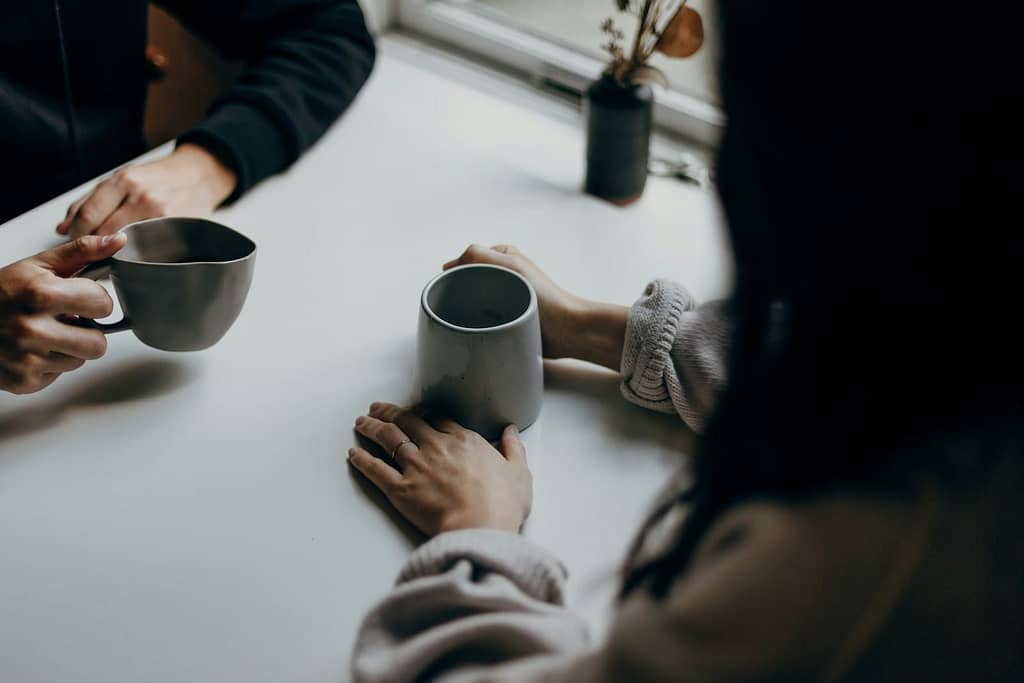 How The Enneagram And Tarot Work Together 4 Two people having a quiet conversation over coffee, symbolising the kind of reflective, supportive space created by combining tarot with the enneagram.