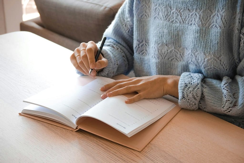 7 Brutally Honest Tips Before Your First Tarot Reading Woman in white and gray sweater writing on white paper