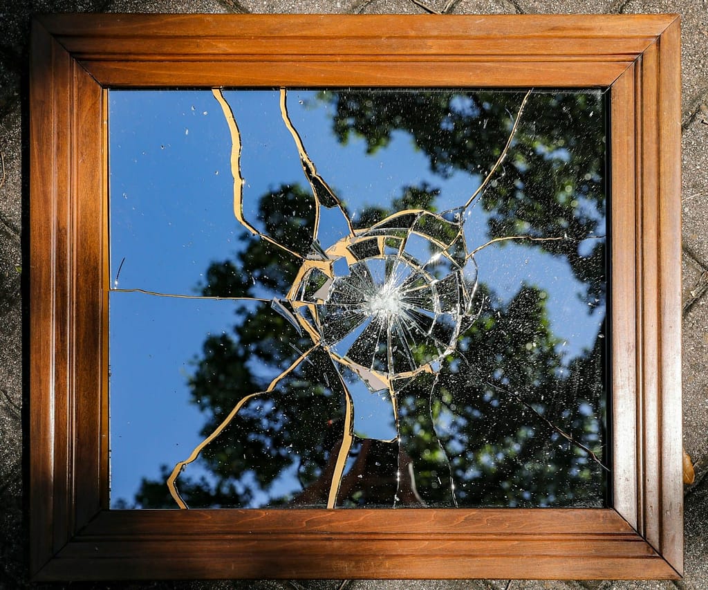 How The Enneagram Helped Me Understand Myself (Eventually) 2 Broken mirror reflecting trees and sky, symbolising the disconnection and confusion often felt by type nine before self-awareness begins.