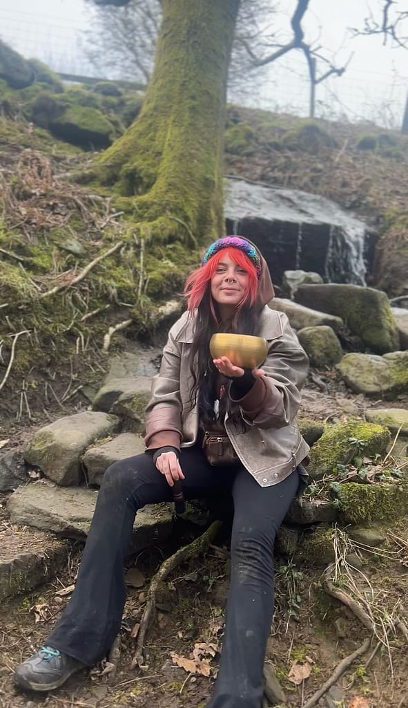 Liv holding a Himalayan singing bowl  in the woods
