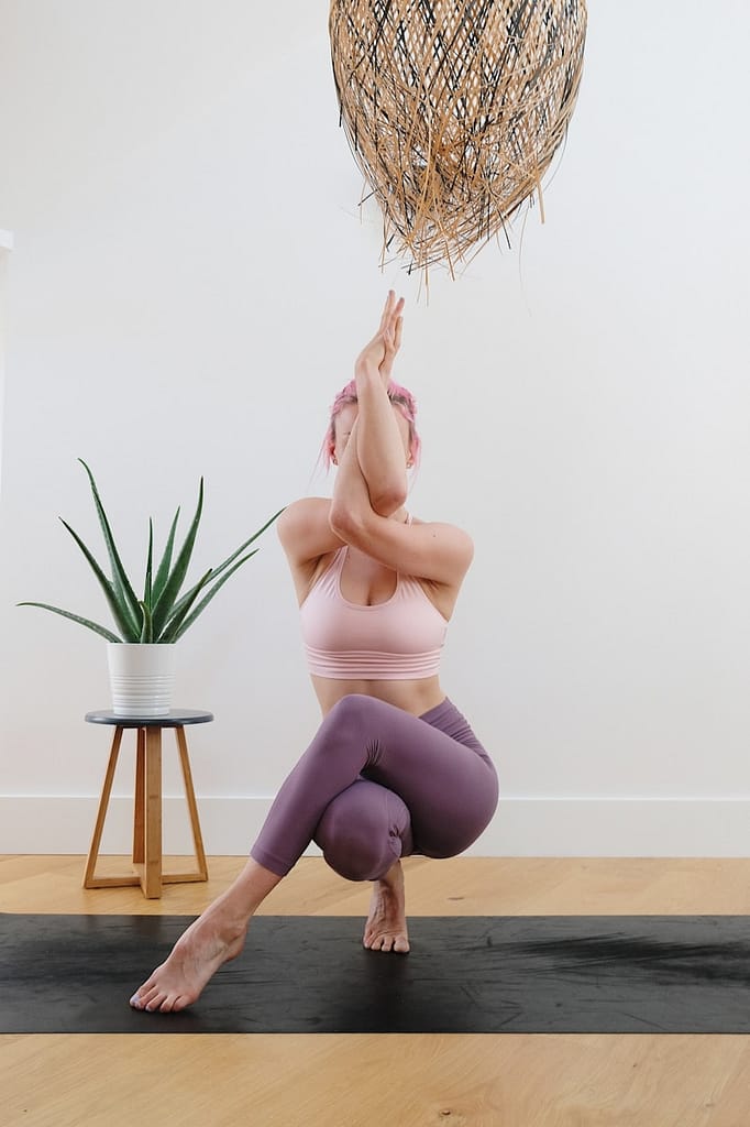 Person practising one of the main types of yoga, performing an eagle pose in a calm indoor studio setting.