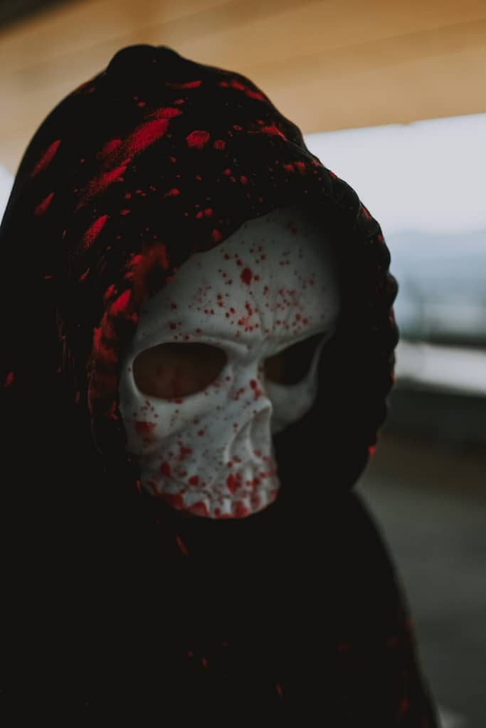 How To Spot A Fake Tarot Reader Person in a skull mask and dark hood representing fake tarot readers who use fear and manipulation, highlighting why this is harmful.
