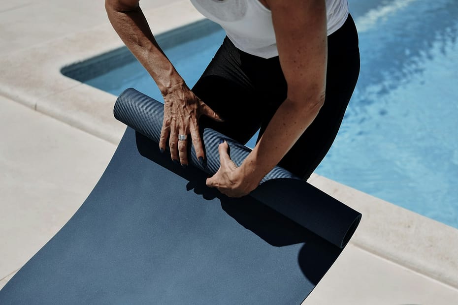 Person rolling up a yoga mat after class, reflecting on the types of yoga explained in this guide.