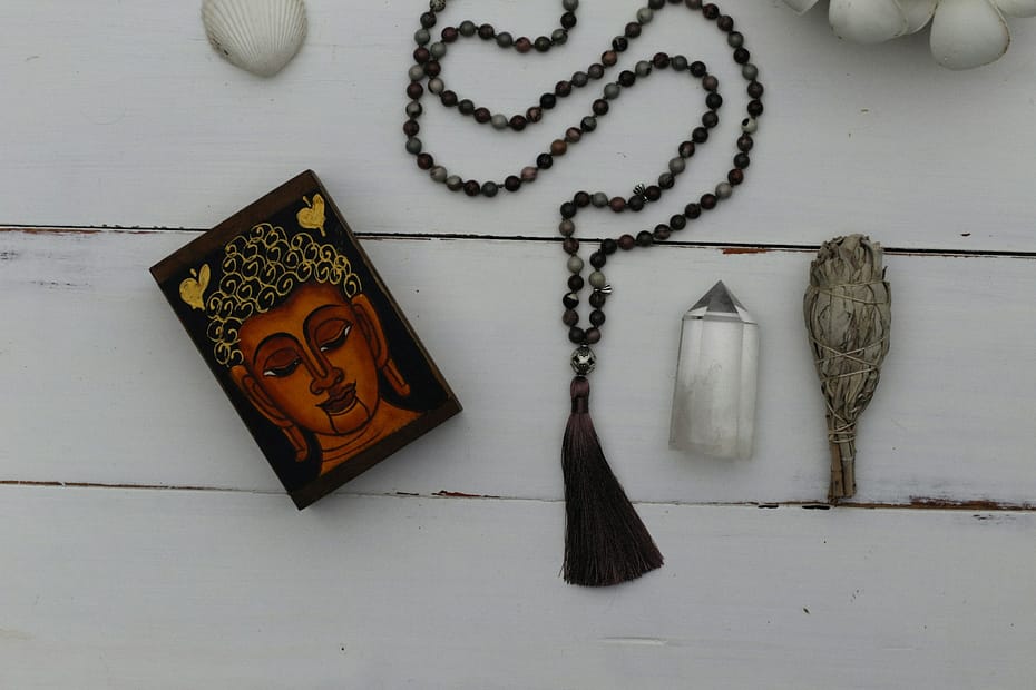 Spiritual tools including a Buddha card, mala beads, and crystals arranged on a white wooden surface – four ways to explore your inner world.